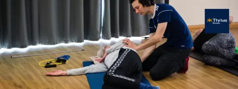 Pilates Instructor, Alex Moore, giving hands-on correction to participant in a small Pilates class for back pain in Broadstone
